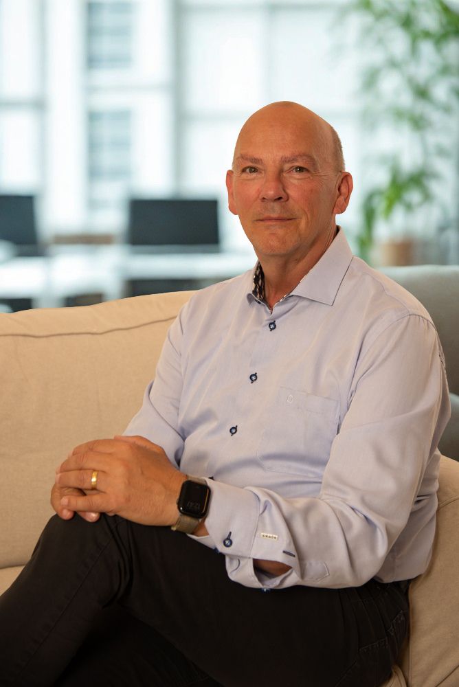 Professionele man in lichtblauw overhemd zittend op beige bank in modern kantoor
