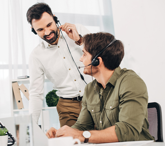 Twee mannen met headsets in een kantoor voeren een videoconferentie of telefoongesprek